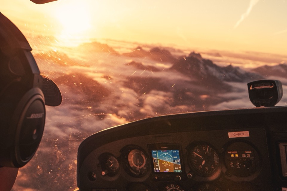 View from a light aircraft cockpit over mountains at sunset